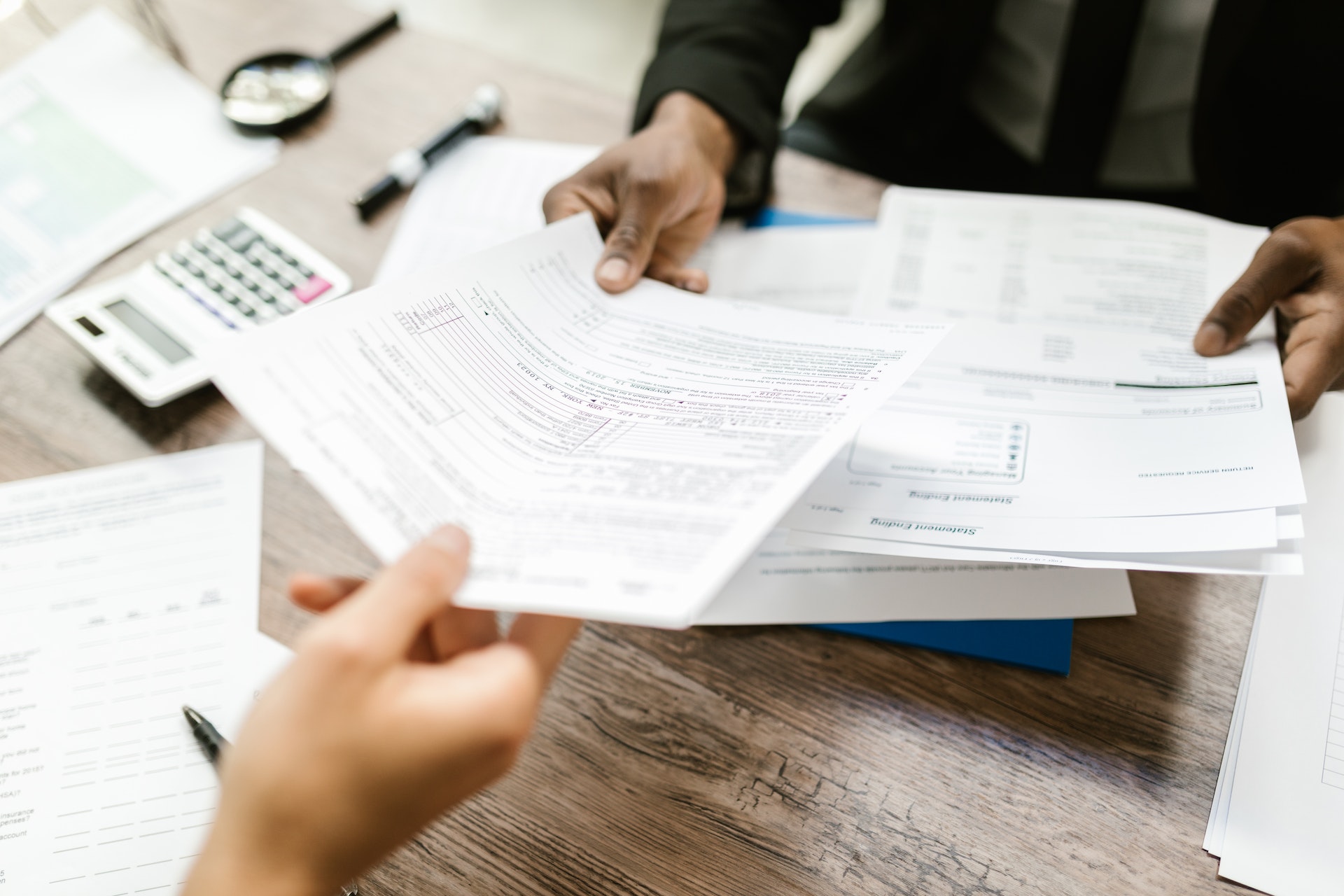 Image of an insurance broker handing paperwork to a person. Photo by RODNAE Productions: https://www.pexels.com/photo/handing-out-of-documents-7821684/